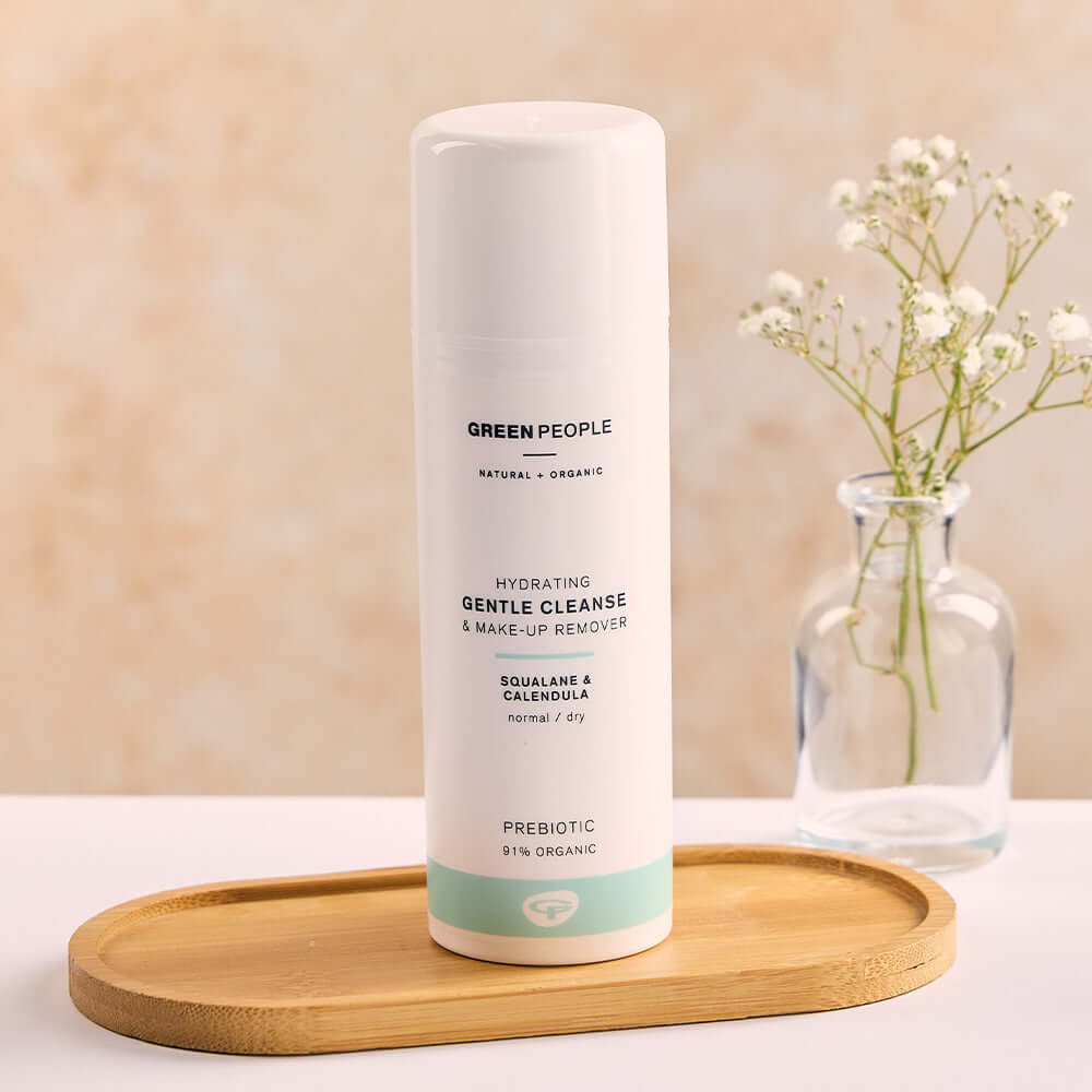 Green People Hydrating Gentle Cleanse and Make-Up Remover standing on a wooden tray beside a glass vase with white flowers.