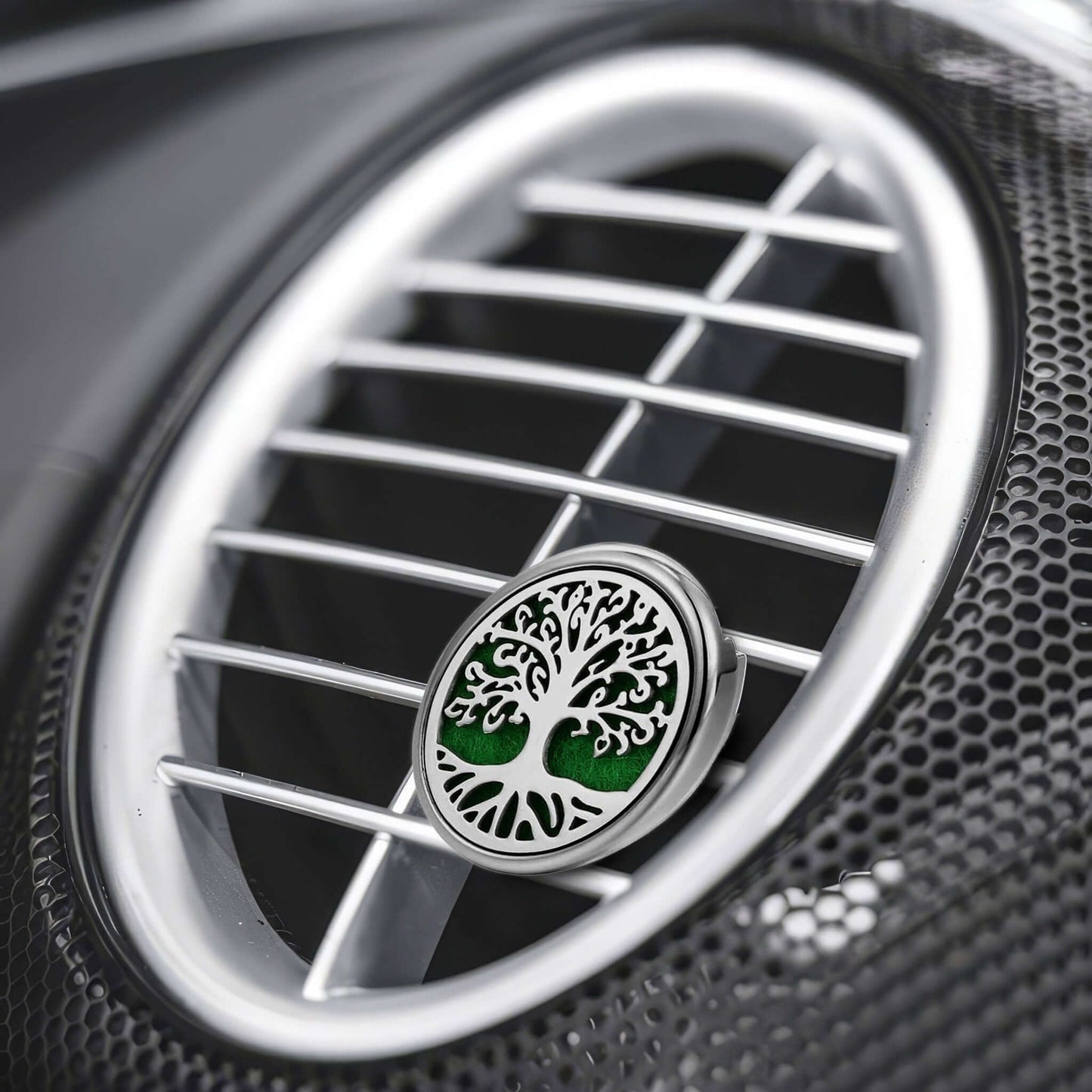 Close-up of a car air fan with a distinctive air freshener featuring a tree design.