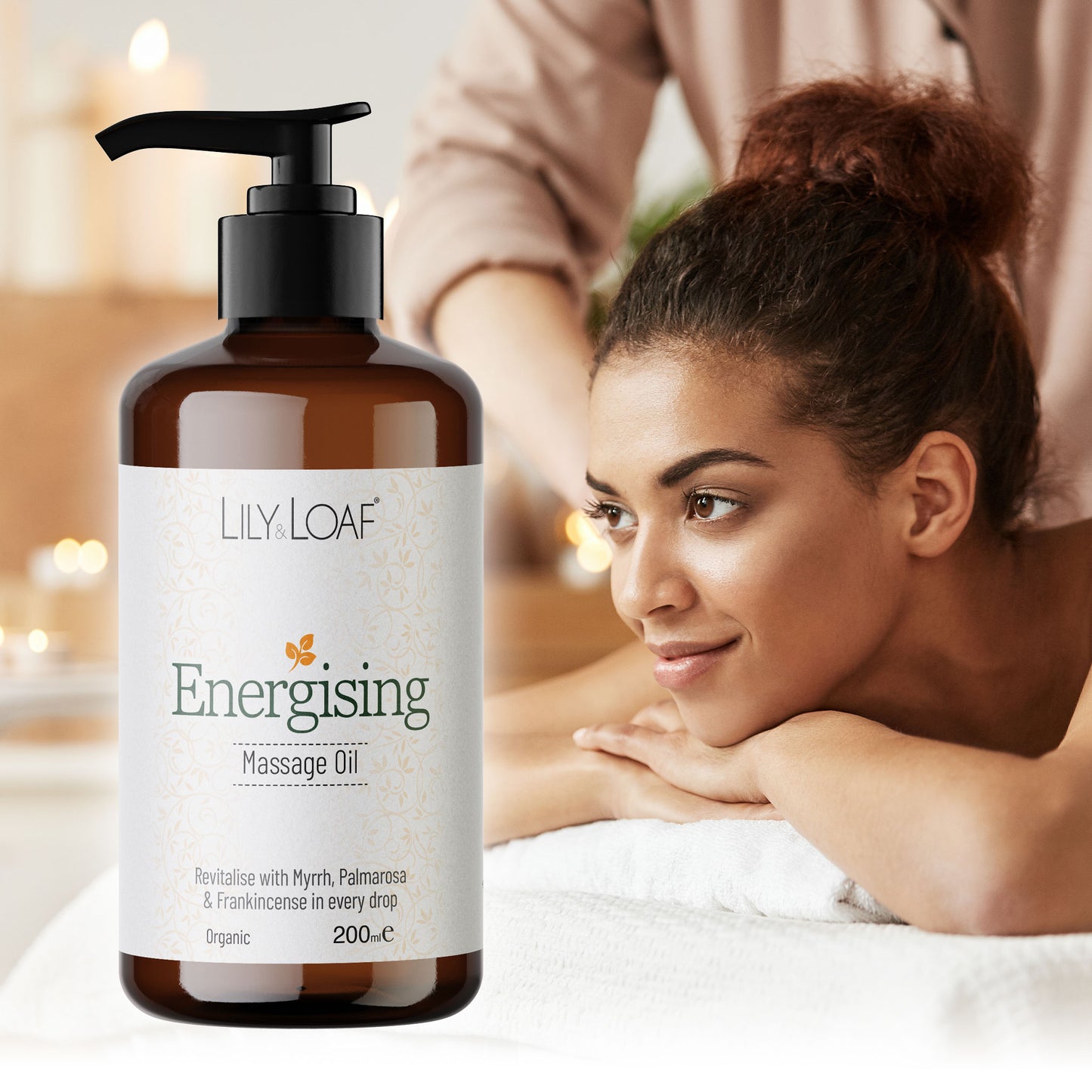 Bottle of Lily & Loaf Energising Massage Oil with a woman receiving a massage in the background