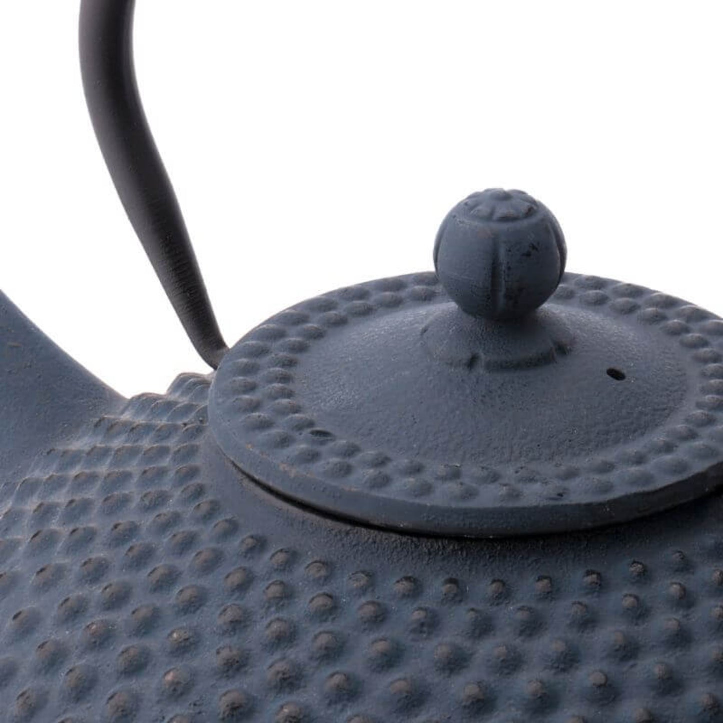 Close-up of a textured black teapot with a lid on a white background