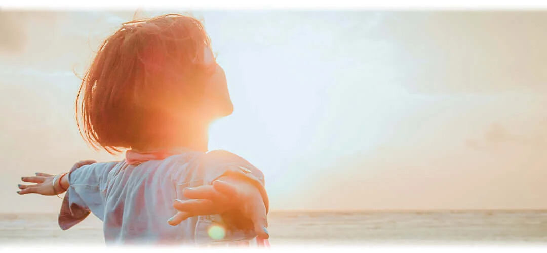 A serene image featuring a person meditating in a peaceful natural setting, surrounded by sunshine. The scene conveys a sense of overall well-being and mindfulness.