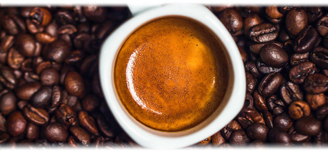 A cup of strong coffee surrounded by coffee beans