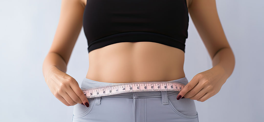 female measuring her waist after dieting with supplements