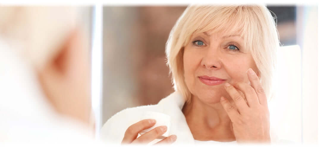 A woman scrutinising her face for wrinkles in the mirror