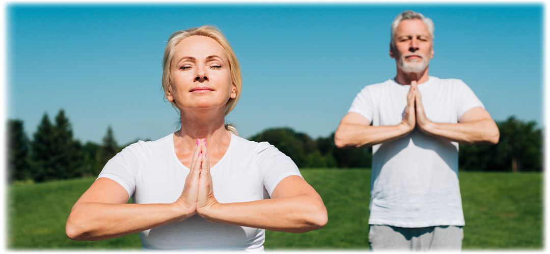 Couple meditating in a green field on a sunny day