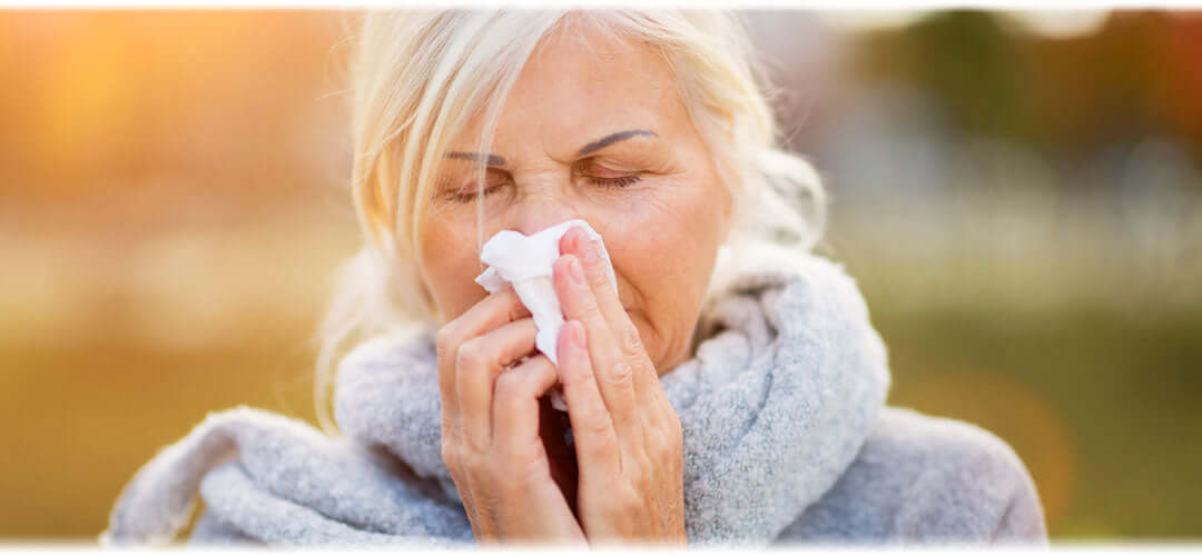 A woman wrapped in a blanket, holding a tissue