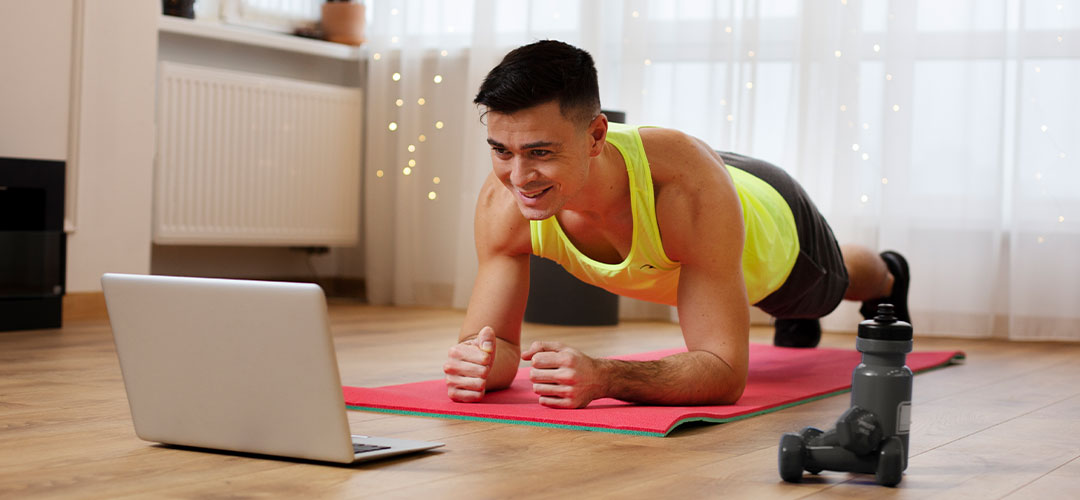 Man doing a plank exercise at home while following an online workout, highlighting tips for creating a sustainable home fitness routine