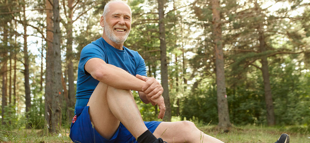 eople-nature-sports-leisure-concept-happy-carefree-retired-man-with-gray-stubble-sitting-comfortably-grass-pine-forest-keeping-elbow-knee-having-rest-after-cardio-exercise-outdoor