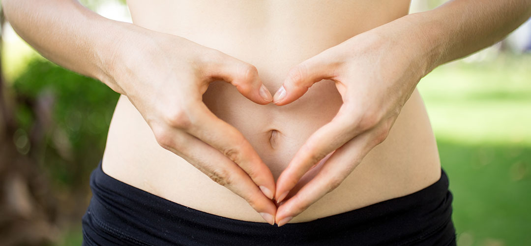 close-up-female-hands-shaping-heart-belly