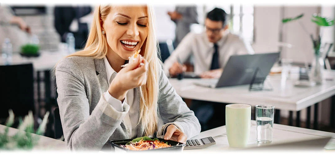 A person eating lunch in an office at their desk