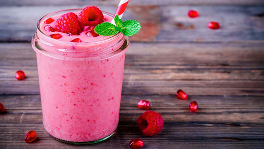 Raspberry protein smoothie served in a glass with berries and mint.