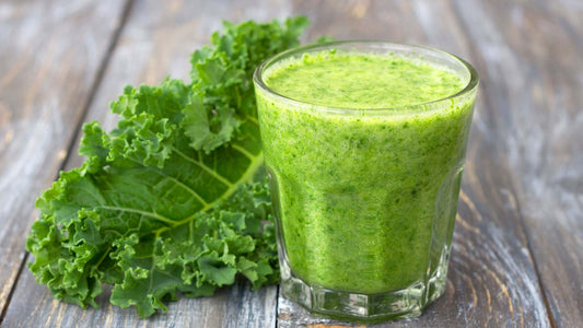 Green kale and tropical protein smoothie served in a glass with fresh kale leaves and banana
