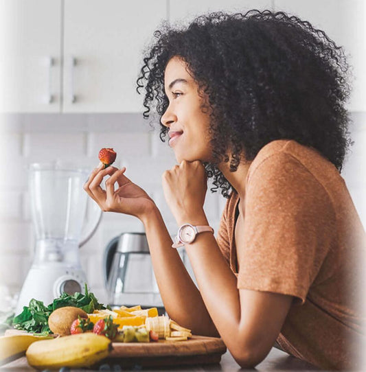 A woman eating a strawberry and smiling