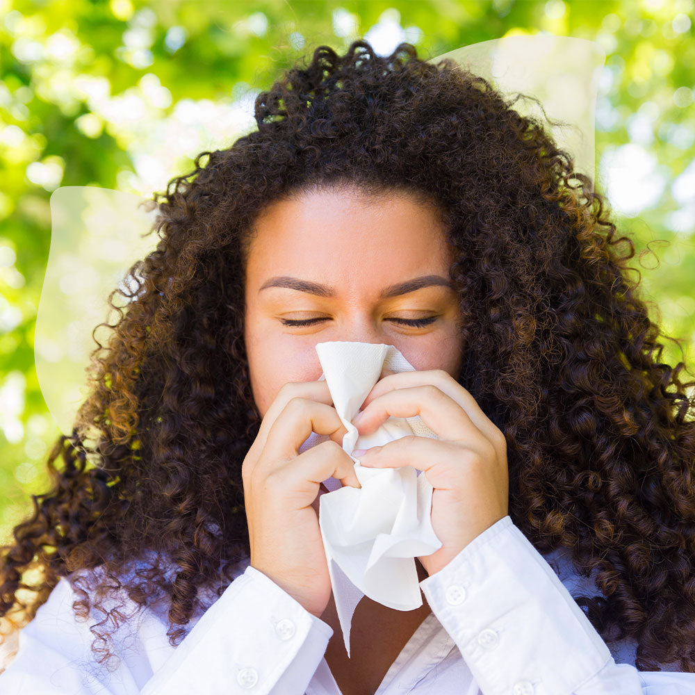 Woman with curly hair blowing her nose outdoors
