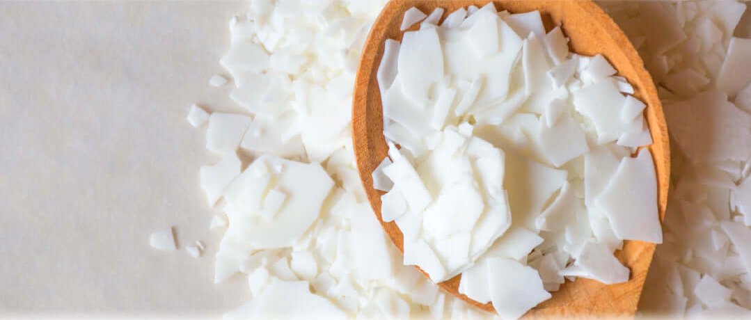 Flakes of white Soy Wax on a wooden spoon