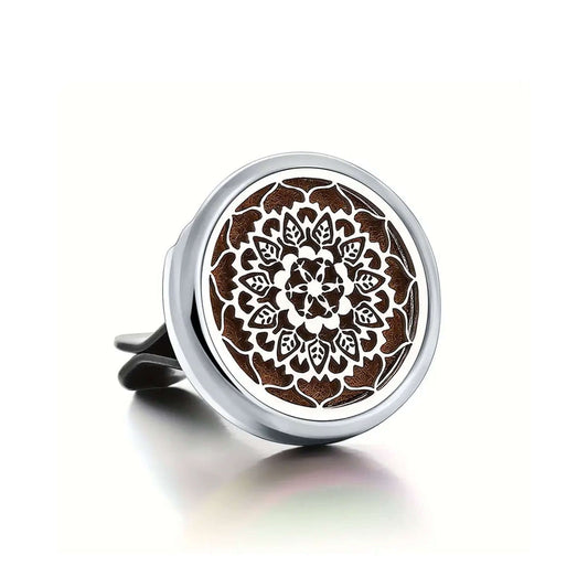 Round metal car air freshener with intricate design on a white background