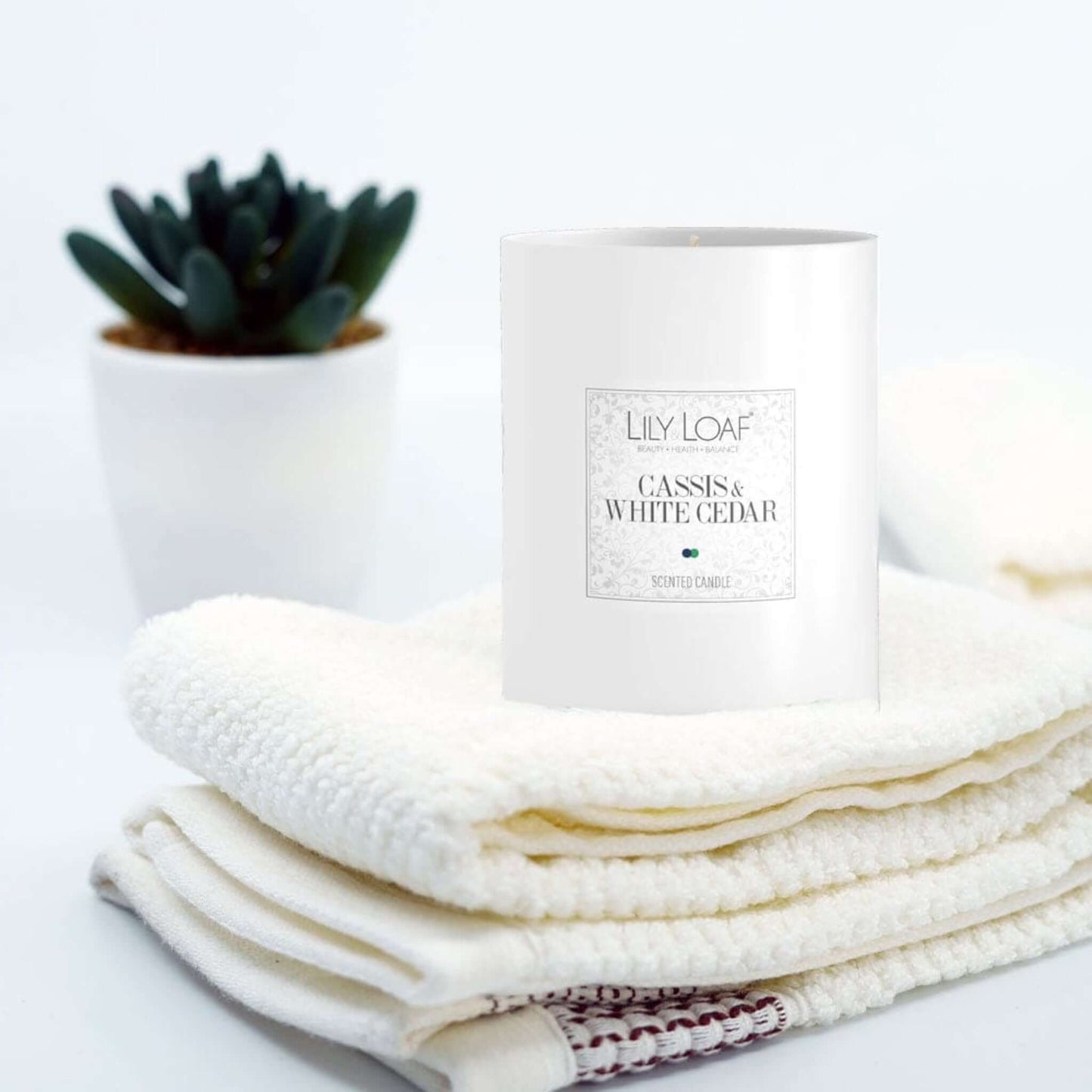 Cassis and White Cedar Soy Wax Candle on stack of fresh white towels