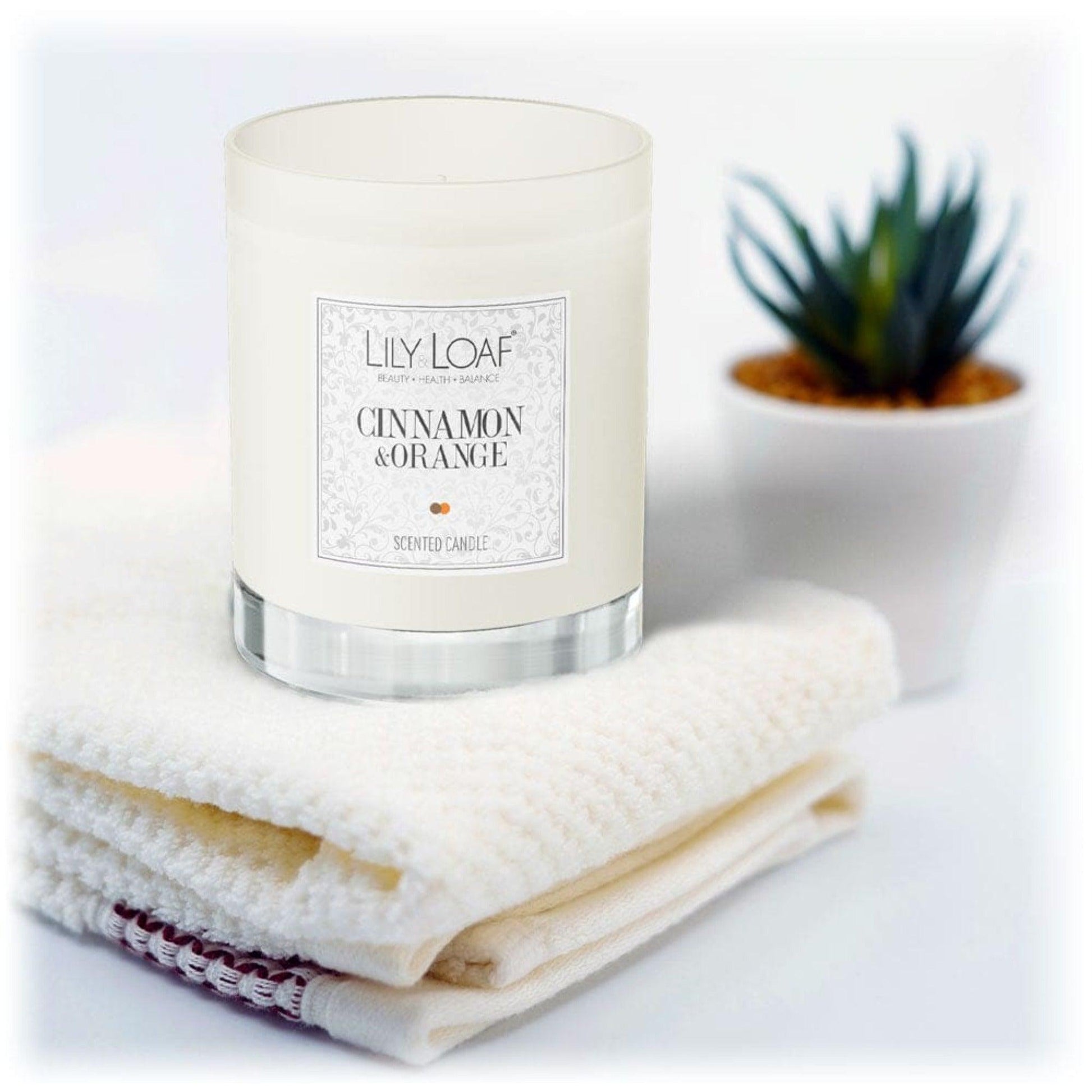 Lily & Loaf Cinnamon and Orange Soy Wax Candle on a stack of fluffy white towels
