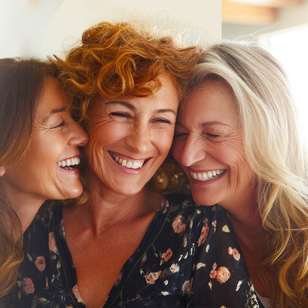 Three women with different coloured hair smiling closely together