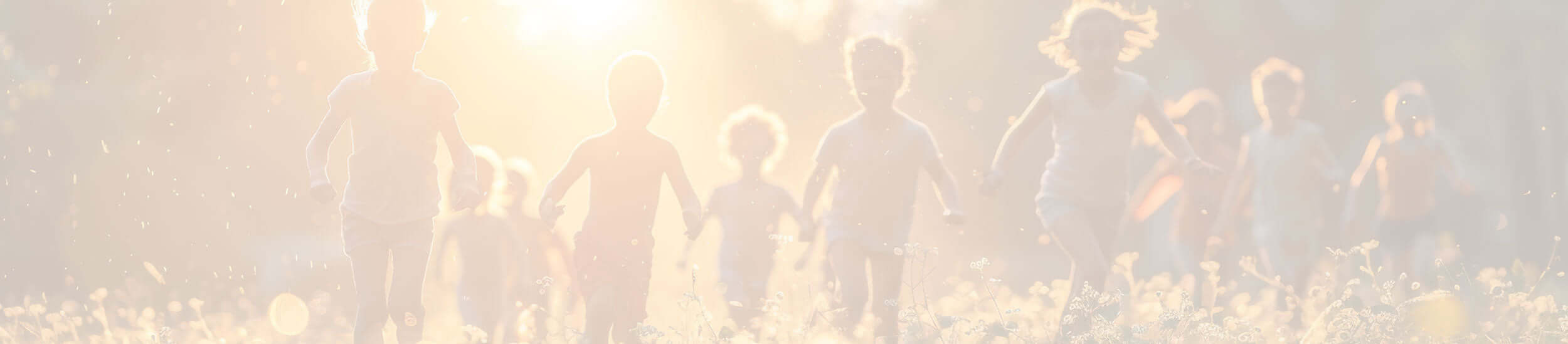 A group of children holding hands and running through a meadow