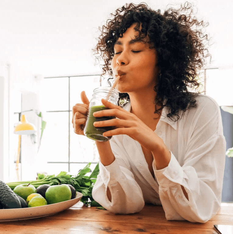 A woman enjoying a green smoothie