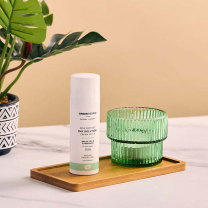 Green People Day Solutions Cream on a nightstand