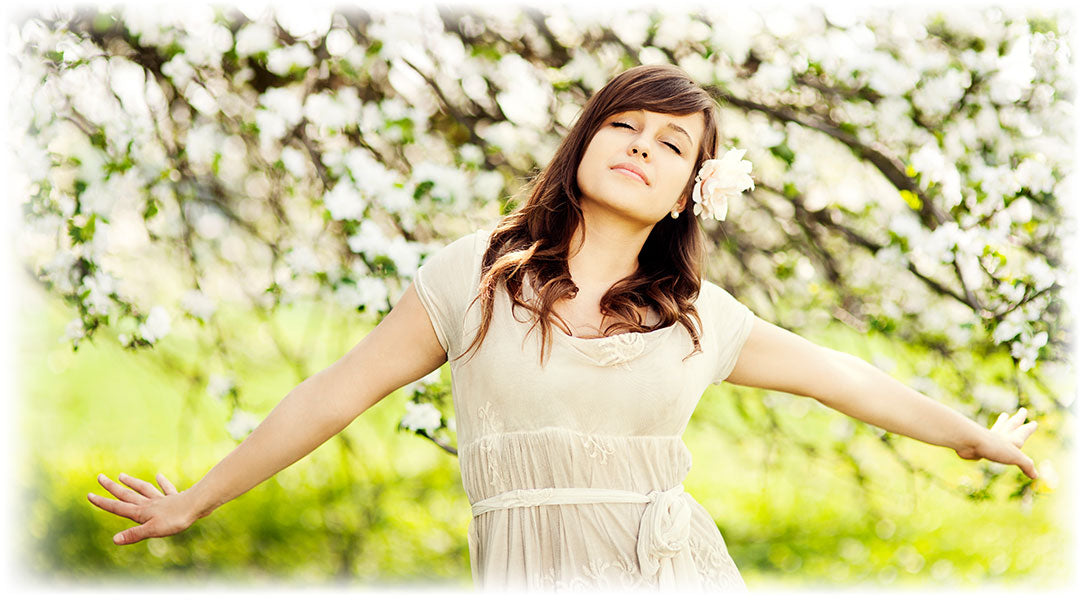 Woman in serene bliss among blossoms, epitomizing Lily & Loaf's commitment to natural beauty and wellness.