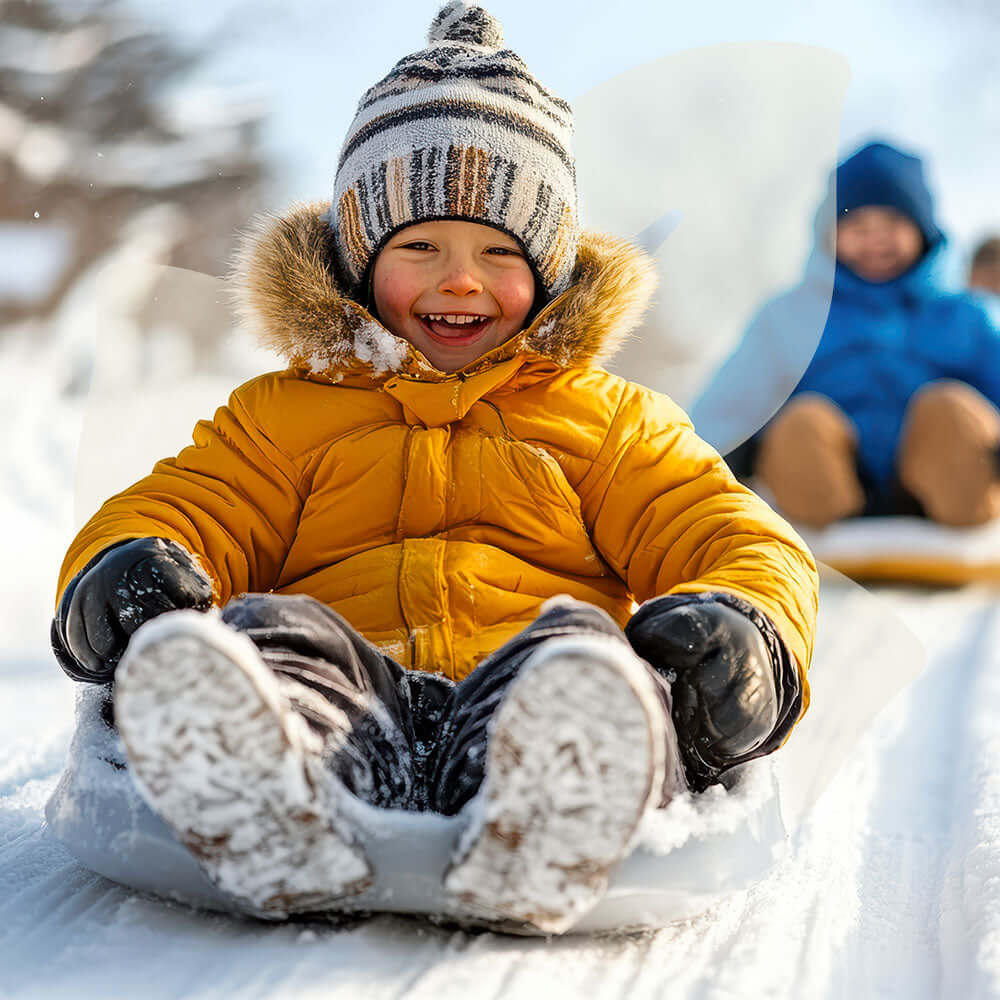 Child in yellow winter coat and striped hat sitting on a sled in the snow