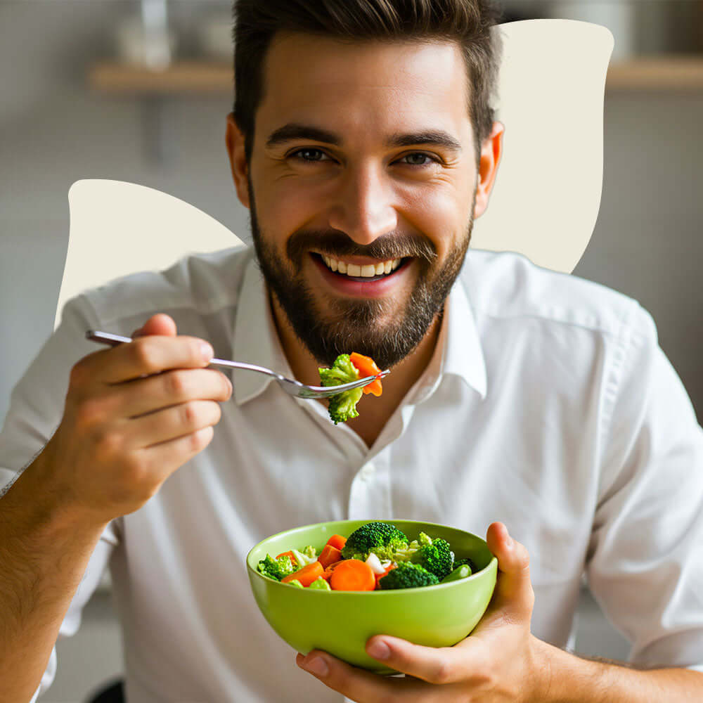 Man eating a bowl of salad with a smile, indicating good digestive health