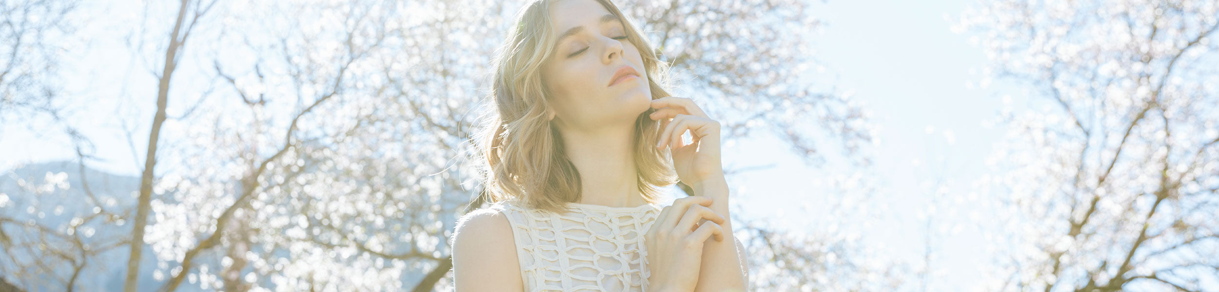 A serene looking woman in a forest on a sunny day