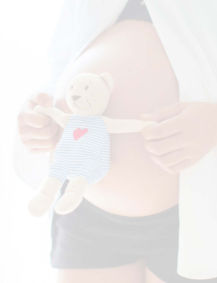 Pregnant lady holding a small cute teddy gain her bump