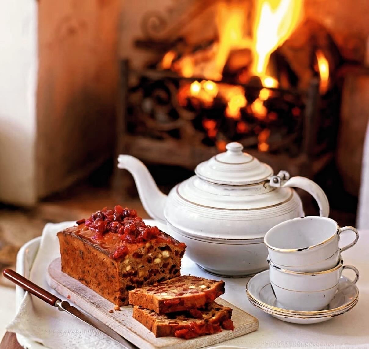 Tea set with cake on a table in front of a fireplace