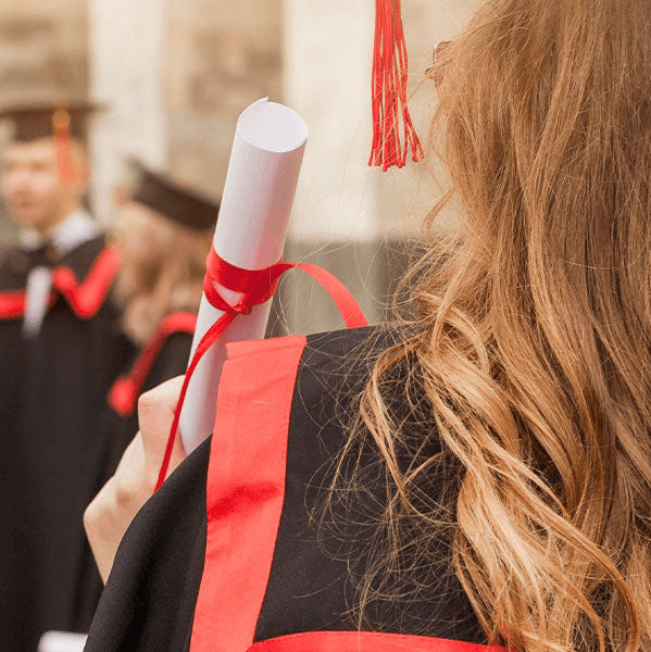 A woman holding a university diploma wearing a cap and gown