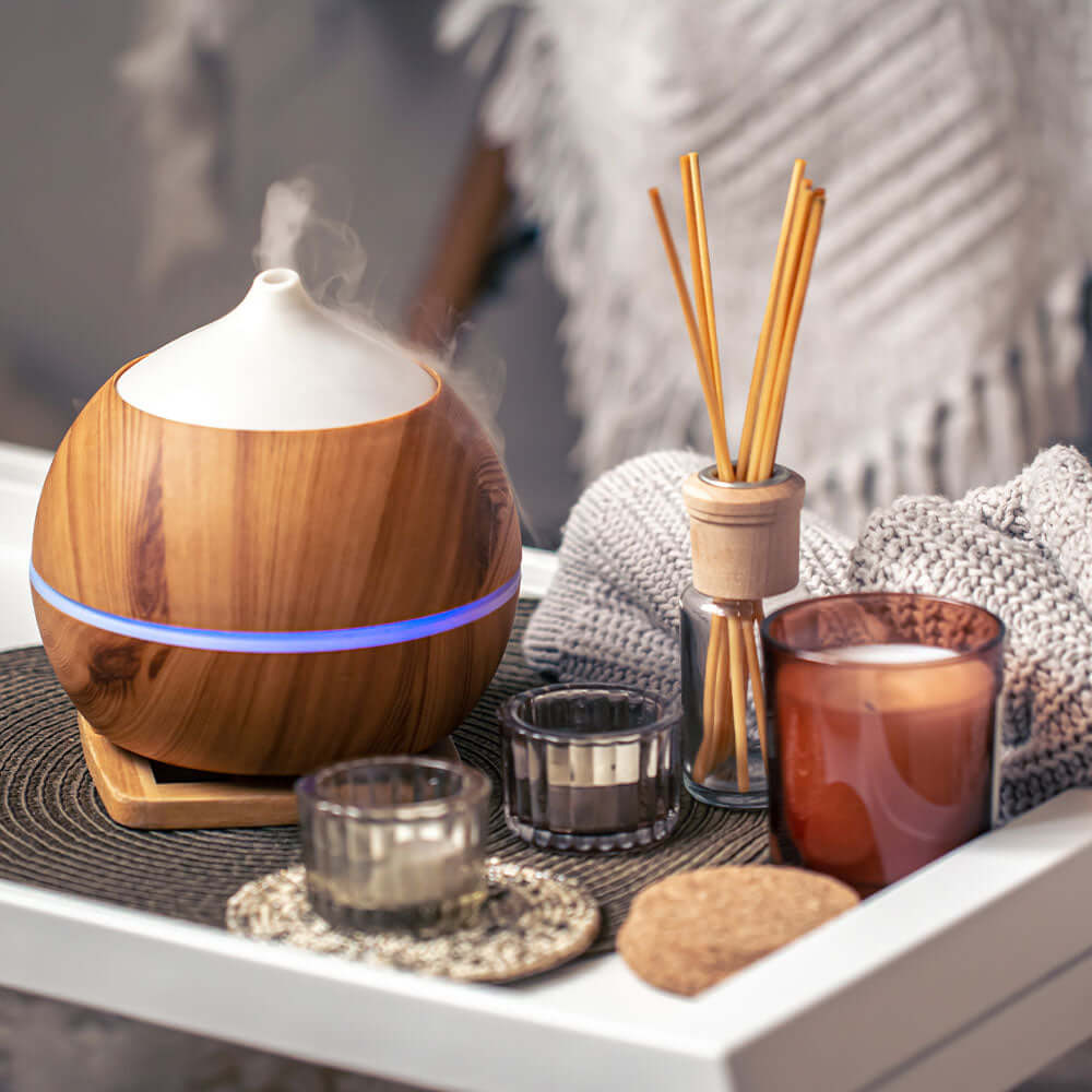 A table filled with cosy Hygge items for winter aromatherapy wellness including diffusers and candles