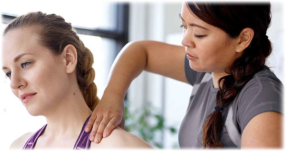 Therapist performing a shoulder massage on a woman, focusing on relieving tension and promoting relaxation and wellness.