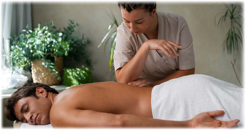 Male client receiving a back massage from a therapist in a serene setting with plants, promoting relaxation and wellness.