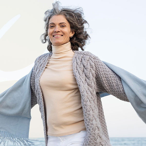 Woman wearing a beige turtleneck and gray cardigan with a blurred background