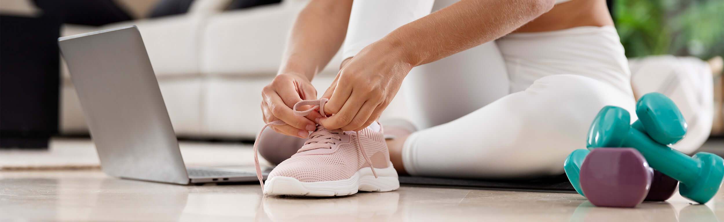 A person tying their trainers next to some weights