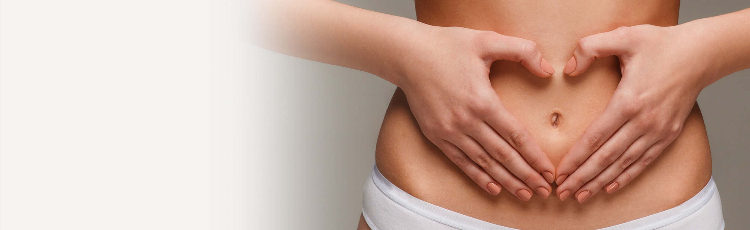 A woman holding her hands against her stomach in a love heart shape