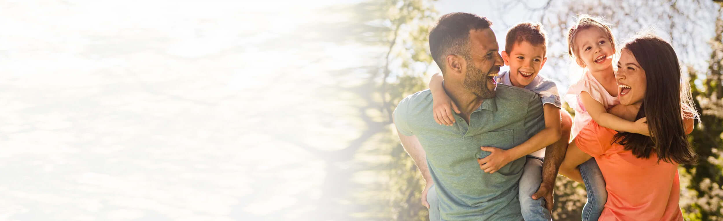 Parents giving their children piggy back rides in a forest