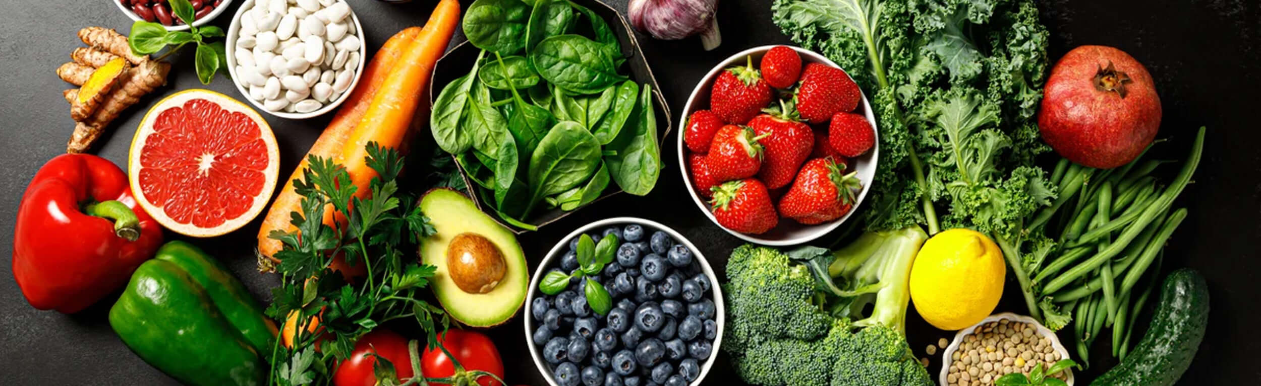 A colourful arrangement of fruits and vegetables including strawberries, blueberries and spinach