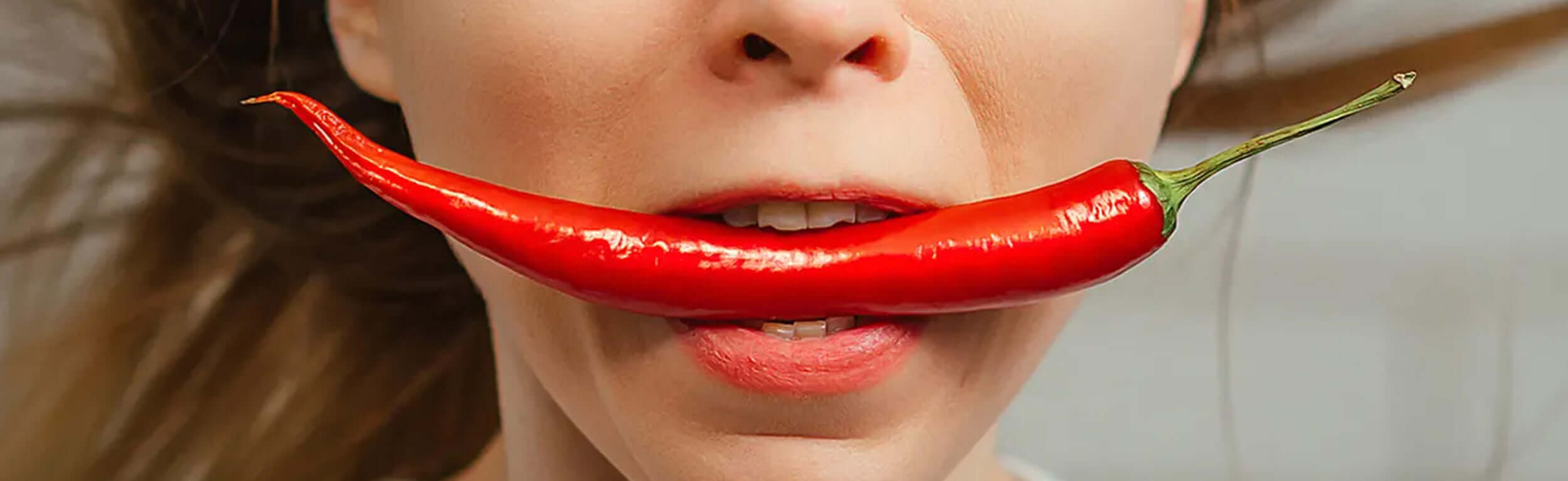 lady about to bite into a large red chilli