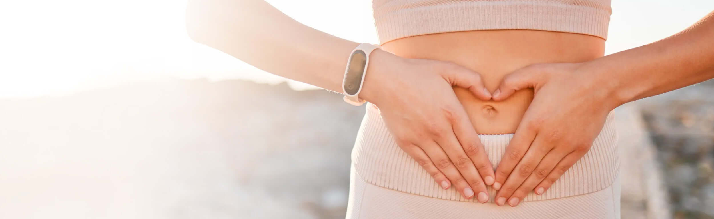 fingers creating a heart against a lady's tummy