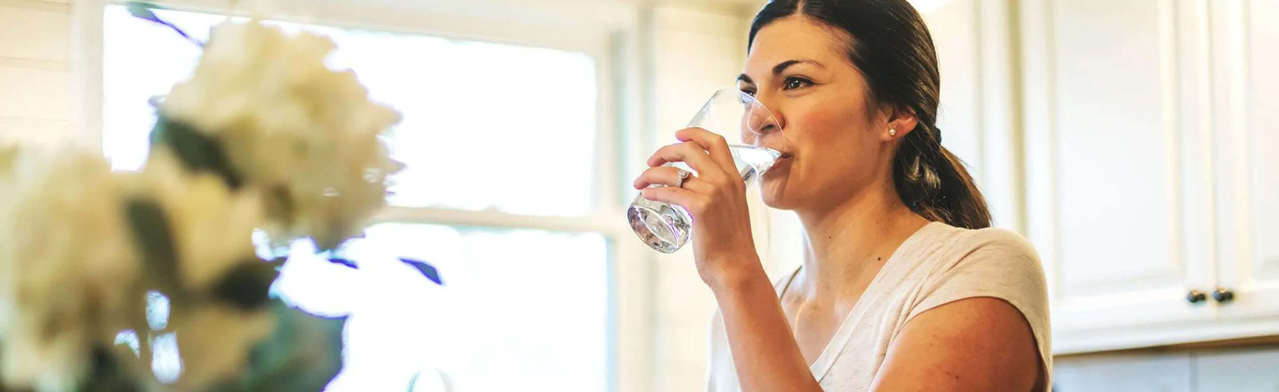 lady drinking a glass of water in the kitchen