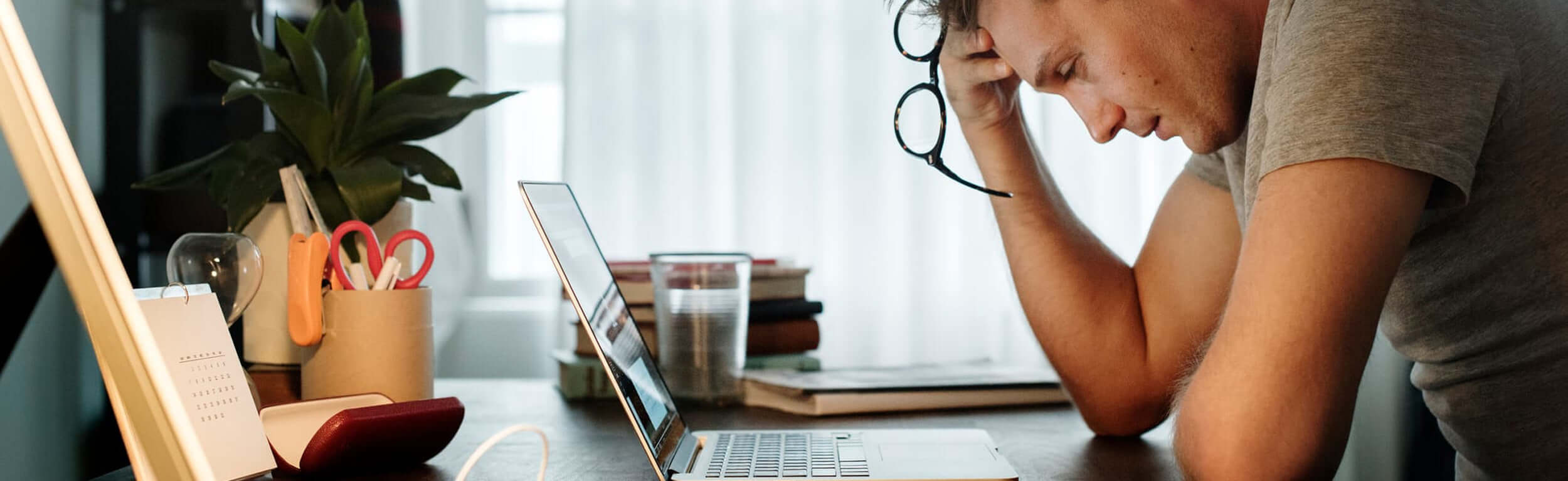 A man looking stressed sat at his laptop