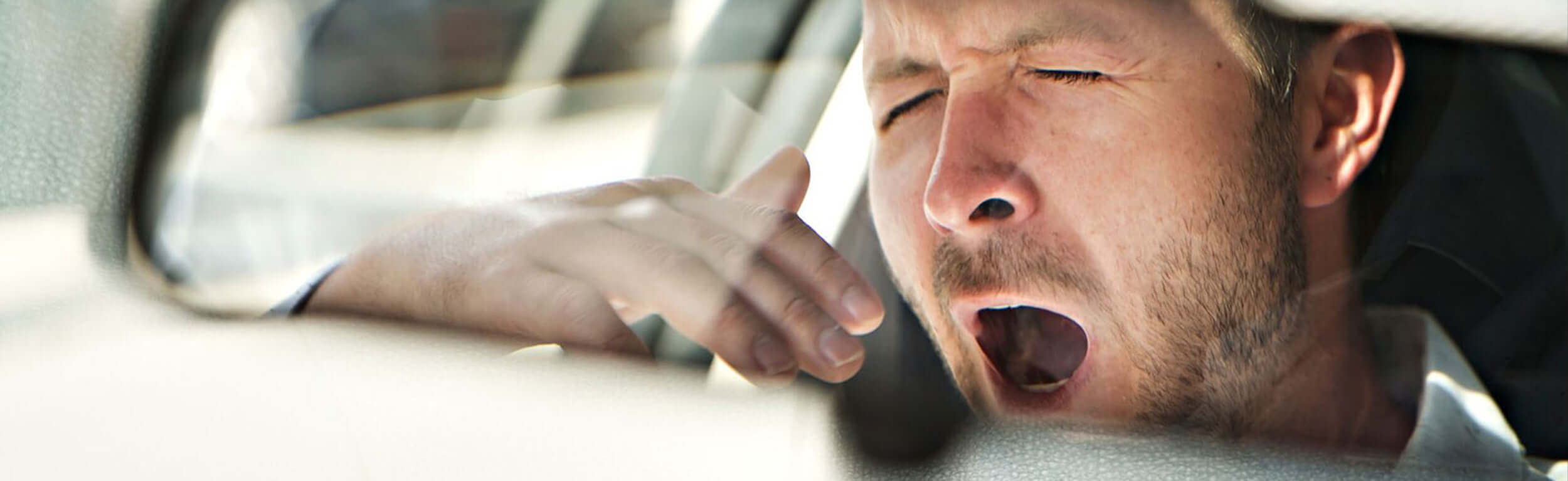 A man yawning in the car