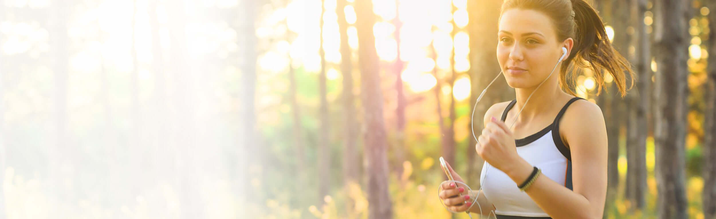 A woman running in the woods listening to music on her earphones