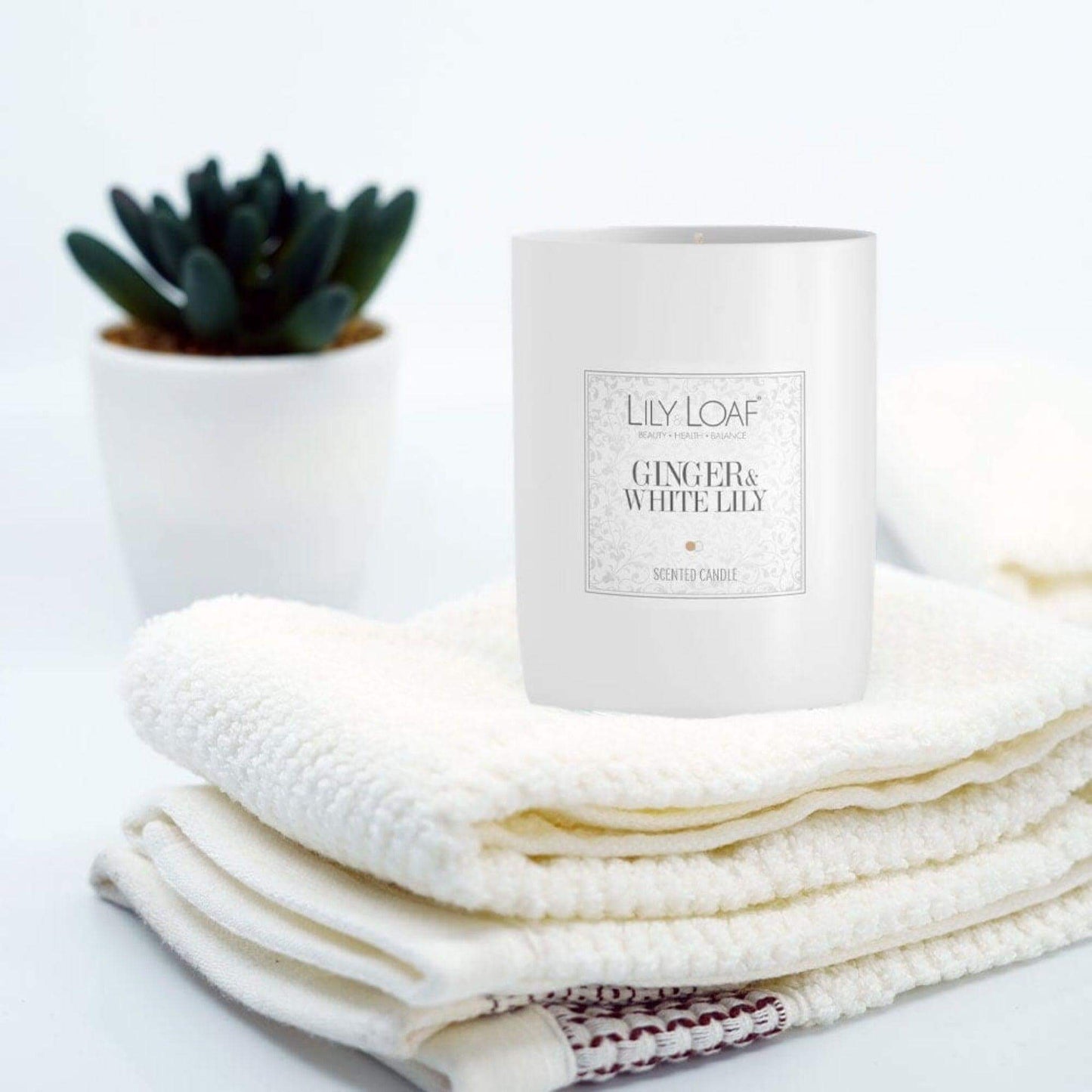 Ginger and White Lily Soy Wax Candle sat up on freshly folded towels