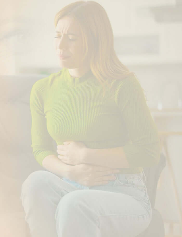 Woman sitting and holding her abdomen, representing digestive discomfort and gut health awareness