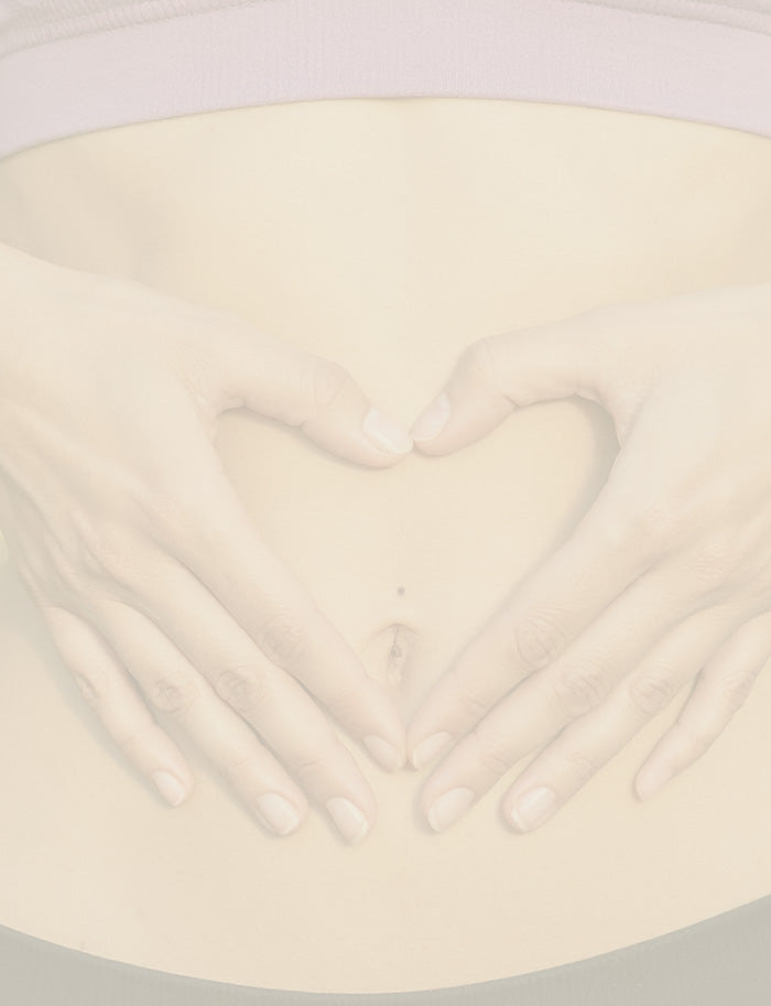 Close-up of a woman holding her hands in a a heart design over her stomach